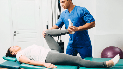 Chiropractor treating a patient with Sciatic pain by elevating her knee and leg towards her chest