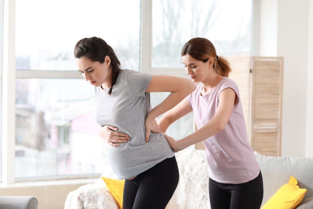 Doula assisting pregnant woman with backpain